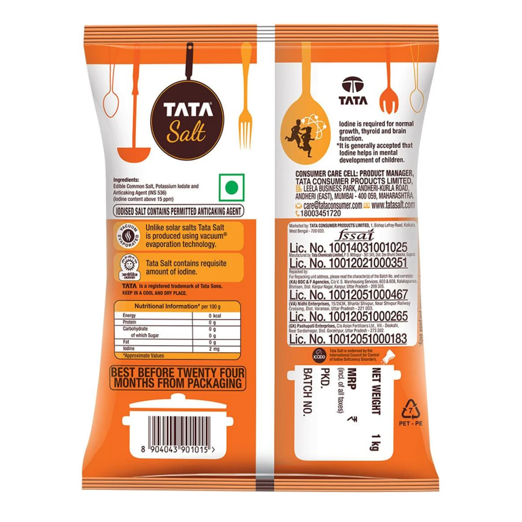 Packet of Tata Iodized Salt standing next to bulk food supplies at Jalaram Food Products warehouse in Ahmedabad.
